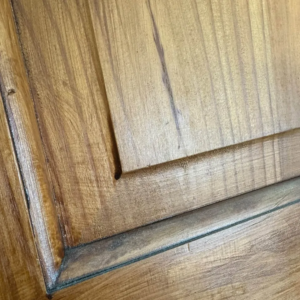 A dull, dusty wooden door panel before cleaning