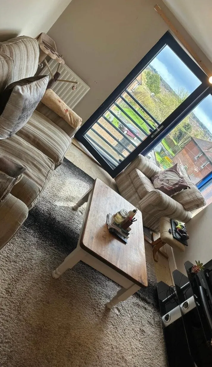 The same living room after cleaning, with a hoovered carpet, tidy sofas and a clear coffee table